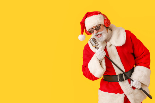 Cool Santa Claus s mikrofonem zpívající vánoční píseň na barevném pozadí - Fotografie, Obrázek