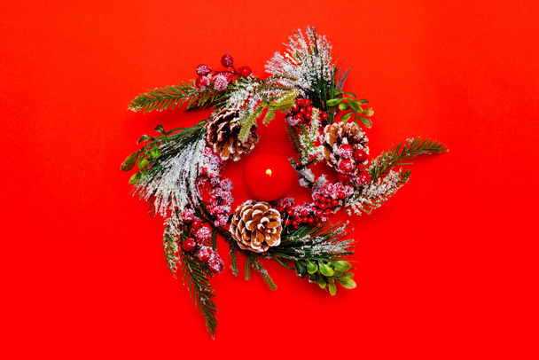 Christmas wreath,burning candle on red bright background. Flat lay, top view,Christmas composition.Copy space. - Фото, зображення