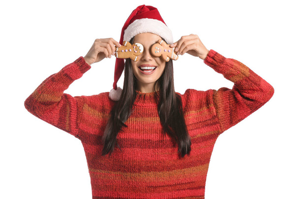 Mooie jonge vrouw in Santa hoed en met lekkere peperkoek koekjes op witte achtergrond - Foto, afbeelding