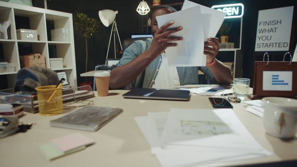 Portret van gestresste Afro-Amerikaanse man faalt met documenten op het werk. - Foto, afbeelding
