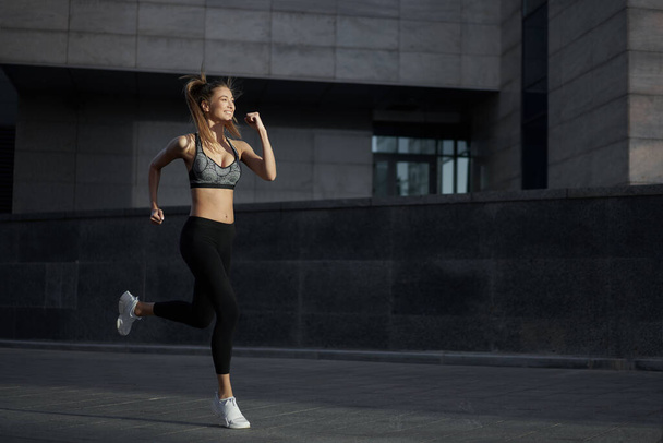 Woman running urban city street background Active sporty caucasian female morning workout Healthy lifestyle concept. Athletic person dressed sportswear do exercises Dark tone mood Corporate building - Photo, image