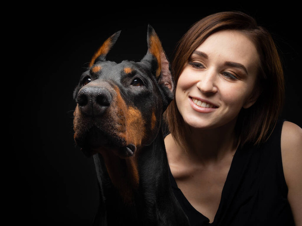 Portret psa Dobermana z właścicielką. Odizolowane zdjęcie Studio na czarnym tle. - Zdjęcie, obraz