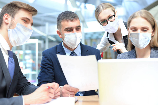 Image of business partners wear preventive masks discussing documents and ideas at meeting. - Foto, Imagem