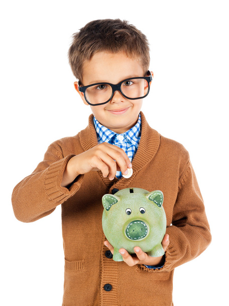 Lächelnder kleiner Junge mit Brille legt Geld in Sparschwein - Foto, Bild