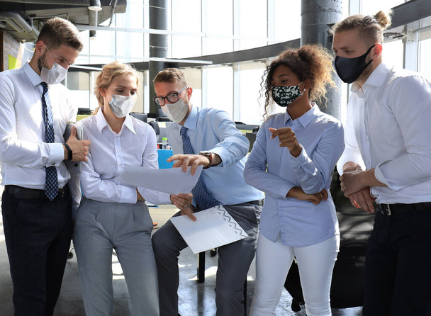Business team in protective masks works in the office. - Foto, afbeelding
