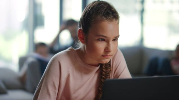 Κορίτσι ψάχνει οθόνη laptop σε εσωτερικούς χώρους. Μαθήτρια με χρήση υπολογιστή εξ αποστάσεως εκπαίδευσης. - Φωτογραφία, εικόνα