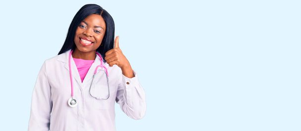 Doktor steteskop takan Afro-Amerikalı genç bir kadın elleriyle mutlu bir jest yapıyor. Kameraya bakıp başarıyı gösteren ifade.  - Fotoğraf, Görsel