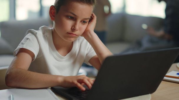 Szomorú gyerek, távolról tanul otthon. Fáradt fiú ül asztalnál számítógéppel. - Fotó, kép