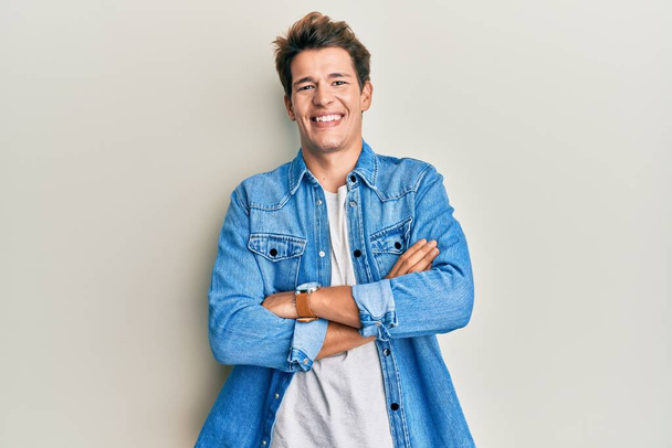 Handsome caucasian man wearing casual denim jacket happy face smiling with crossed arms looking at the camera. positive person.  - Photo, Image