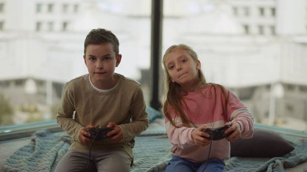 Broers en zussen met gokverslaving. Kinderen die thuis computerspelletjes spelen. - Foto, afbeelding