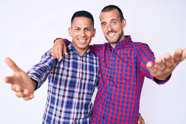 Mladý gayové pár dvou mužů na sobě ležérní oblečení s úsměvem veselá nabídka ruce dávat pomoc a přijetí.  - Fotografie, Obrázek
