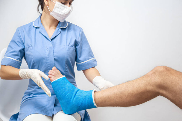 Gros plan de la jambe d'un homme dans un plâtre et une attelle bleue après le bandage dans un hôpital. - Photo, image