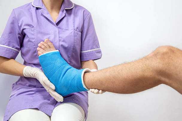 Close-up van het been van een man in een gips en een blauwe spalk na verband in een ziekenhuis. - Foto, afbeelding