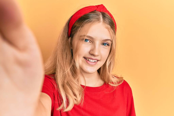 Belle jeune fille caucasienne prenant une photo selfie regardant positif et heureux debout et souriant avec un sourire confiant montrant des dents  - Photo, image