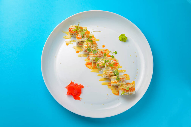 Sushi Set: sashimi and sushi rolls on blue background. Traditional Japanese cuisine concept, close up. Delicious sushi rolls set on white round plate. - Fotó, kép