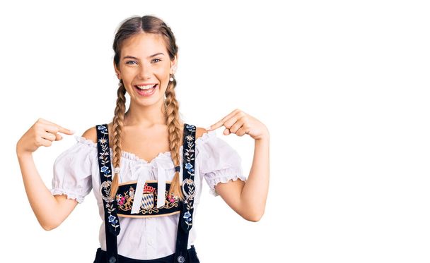 Krásná kavkazská žena s blond vlasy na sobě října slavnostní tradiční oblečení vypadá sebevědomě s úsměvem na tváři, ukazuje se s prsty hrdý a šťastný.  - Fotografie, Obrázek