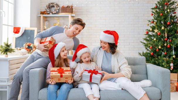 Merry Christmas! Pretty young mother, father and daughters with presents near Christmas tree.  - Fotoğraf, Görsel