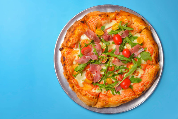 A Pepperoni pizza on a blue background isolated. Traditional Italian cuisine concept, pizza Margarita or Margherita over blue. - Photo, Image