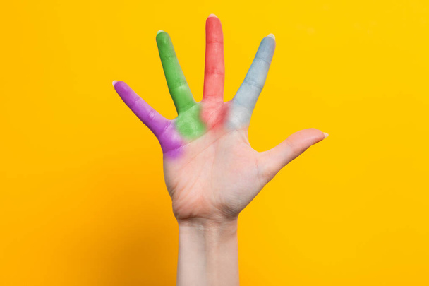 A woman's hand with multicolored fingers spread out. Yellow background. The concept of the world day of protection of children. - 写真・画像