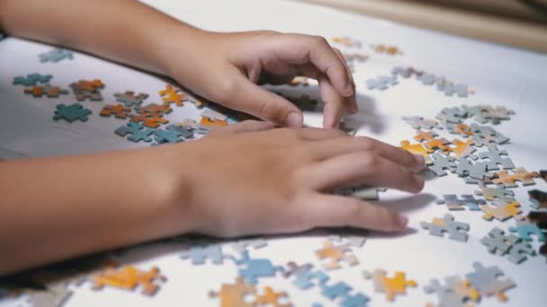 Kinderen handen verzamelen puzzel op tafel. Concept voor kinderontwikkeling. Close-up - Video