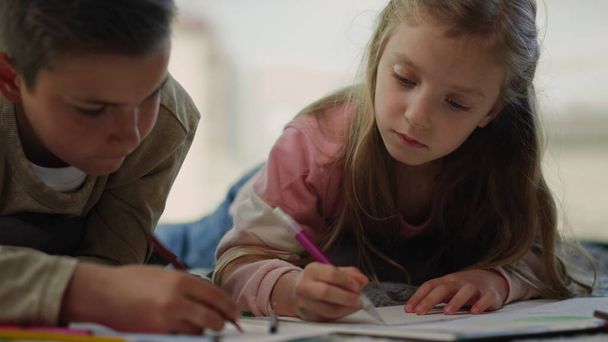 Kinderen schilderen thuis met kleurpotloden. Broers en zussen die schetsboeken gebruiken. - Foto, afbeelding