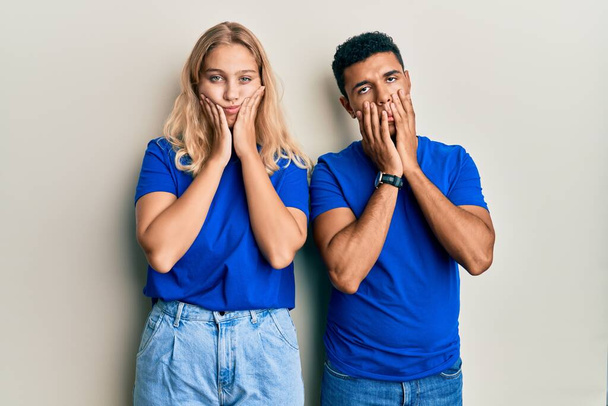 Young interracial couple wearing casual clothes tired hands covering face, depression and sadness, upset and irritated for problem  - Foto, Imagen