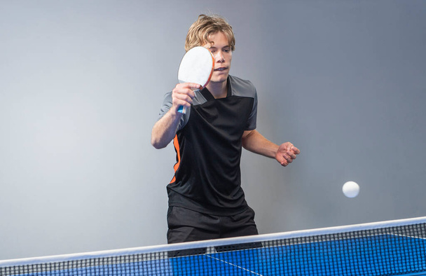 Tiener die ping pong tafeltennis speelt. Uitrusting, bewegend. - Foto, afbeelding