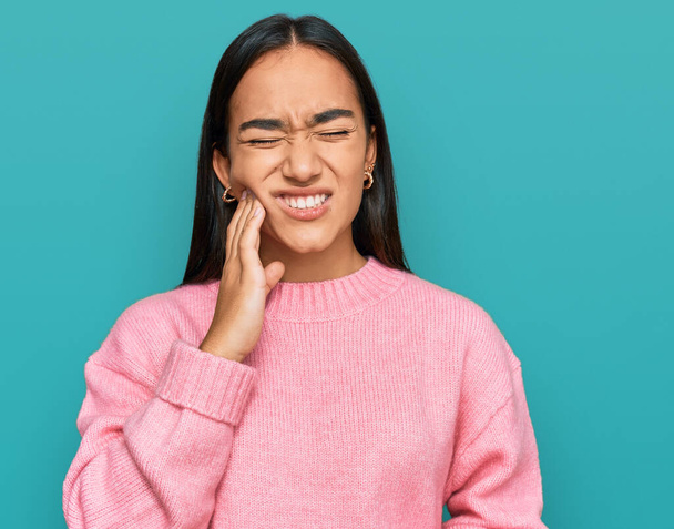 Молодая азиатка, одетая в случайный зимний свитер, касается рта рукой с болезненным выражением лица из-за зубной боли или зубной болезни на зубах. стоматолог  - Фото, изображение