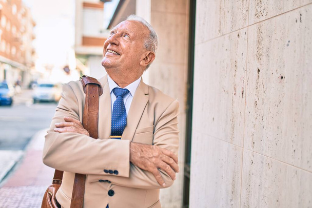 Homme d'affaires âgé aux cheveux gris souriant heureux debout à la ville. - Photo, image