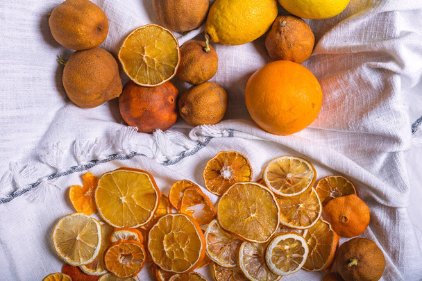 A closeup of dried orange slices and other citruses isolated on the white fabric - orange and tangerine - Fotografie, Obrázek