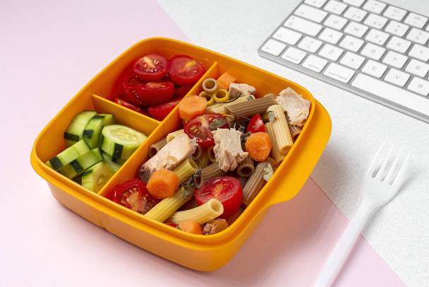 Lunch at work place healthy pasta with tuna, cherry tomatoes, carrot, cucumber in lunch box on work table. Home food for office concept - Foto, Bild