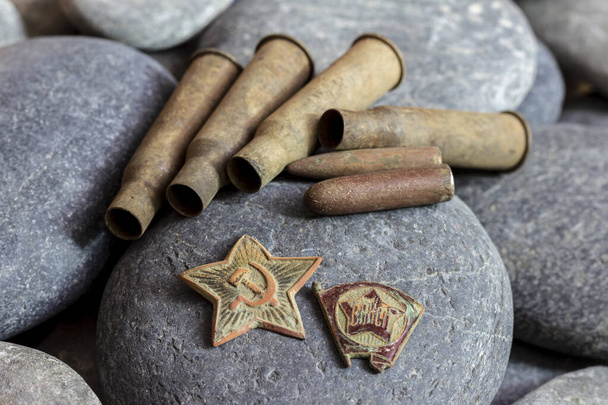 Petrohrad, Rusko - říjen, 02, 2020: Červená hvězda z vojenské čepice a odznak Komsomol, spolu s nábojnicemi a kulkami z pušky Mosin ráže 7,62 mm, jsou artefakty Sovětského svazu. - Fotografie, Obrázek