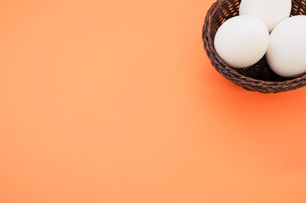 A high angle shot of a basket of eggs on an orange surface - Photo, image