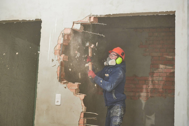 demolition work and rearrangement. worker with sledgehammer destroying wall - Zdjęcie, obraz