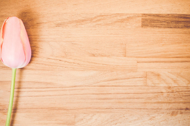 Uma foto aérea de uma flor de tulipa vermelha em uma mesa de madeira com espaço para o seu texto - Foto, Imagem