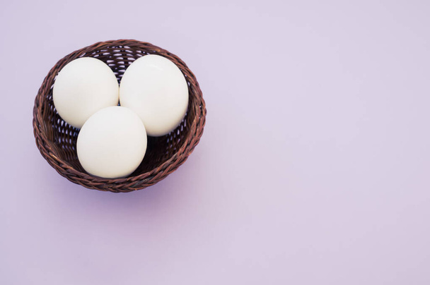 A high angle shot of a basket of eggs on a purple surface - Photo, image