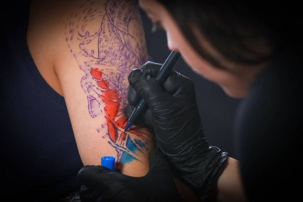 Жіночий художник татуювання робить татуювання на чоловічій руці
 - Фото, зображення