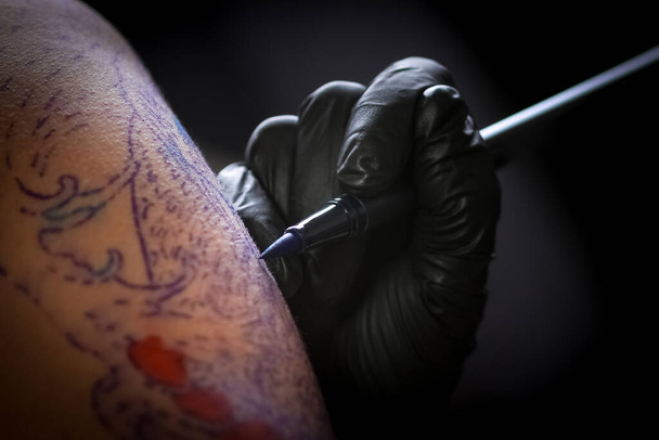 Tatuagem feminina fazendo tatuagem no braço de um homem
 - Foto, Imagem