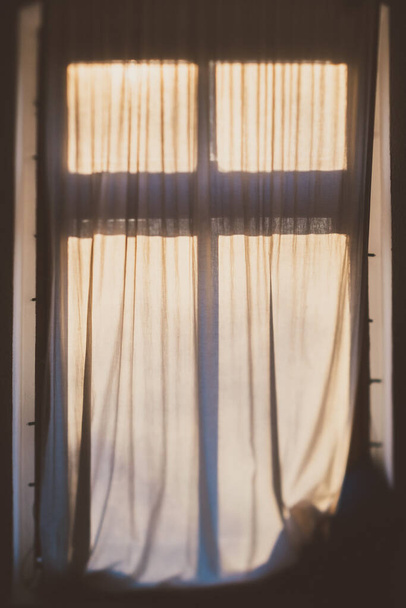A vertical shot of a closed curtain in front of the window in the morning - Φωτογραφία, εικόνα