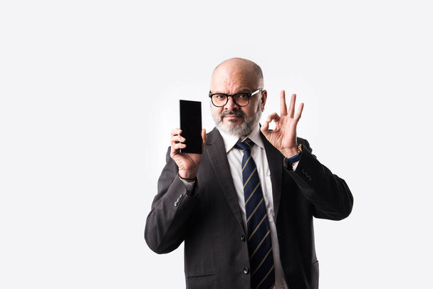 Ritratto di vecchio uomo d'affari asiatico indiano che usa lo smartphone per messaggiare, chiamare o mostrare o presentare su sfondo bianco - Foto, immagini