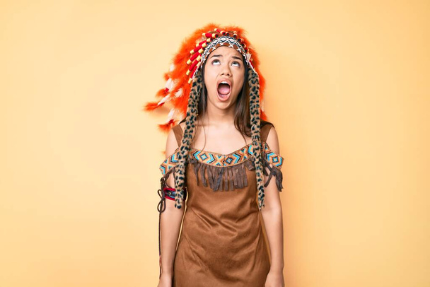 Young beautiful latin girl wearing indian costume angry and mad screaming frustrated and furious, shouting with anger. rage and aggressive concept.  - Fotografie, Obrázek