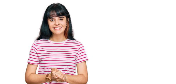 Junges hispanisches Mädchen in lässiger Kleidung mit zusammengelegten Händen und erhobenen Fingern, die entspannt und fröhlich lächeln. Erfolg und Optimismus  - Foto, Bild