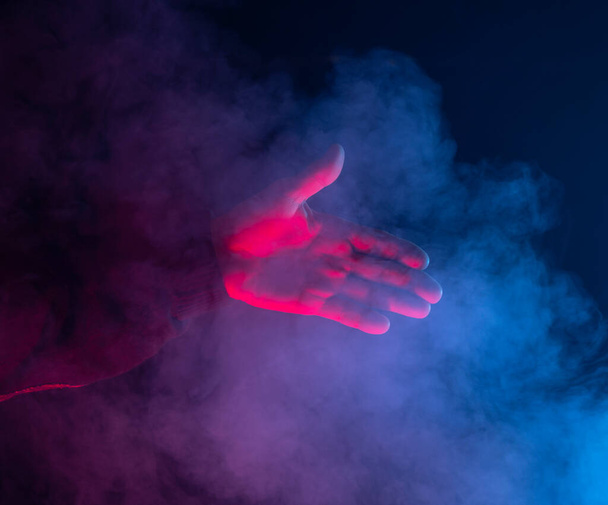 Handdruk. Man hand voor schudden over donkere rokerige achtergrond - Foto, afbeelding