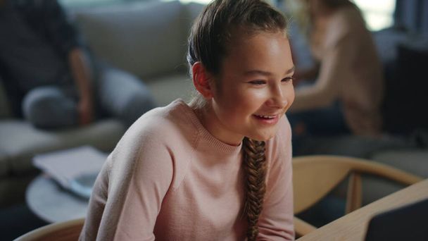 Chica alegre buscando pantalla portátil en casa. Sonriente niño usando la computadora. - Foto, imagen