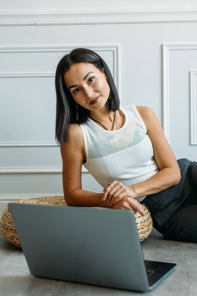 アジア系の美少女で自宅でウェブ会議をしノートパソコンと携帯電話を手に - 写真・画像