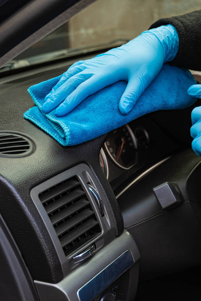 Las manos en guantes de goma azul frotan el salpicadero de un coche. Limpieza interior del coche, pulido. Primer plano - Foto, imagen