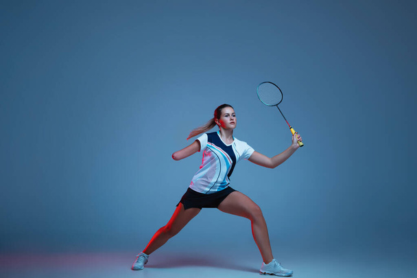 Beautiful handicap woman practicing in badminton isolated on blue background in neon light - Foto, Imagem