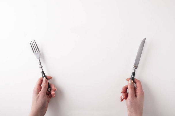 Beyaz arka planda çatal ve bıçak tutan kadın eller. Bıçak ve çatal beyaz arkaplanda izole edildi - Fotoğraf, Görsel