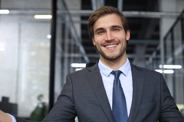 Young handsome businessman smiling in an office environment - Foto, Imagen