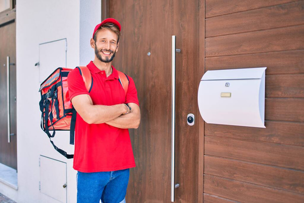 Caucasian delivery man wearing red uniform and delivery backpack smilly happy outdoors - Photo, Image
